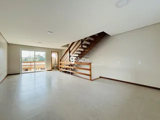 Ambiente interno de uma sala ampla com piso de porcelanato e escadaria de madeira.