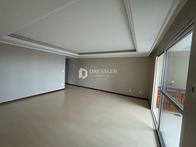 Interior de uma sala com piso de madeira clara e paredes brancas.