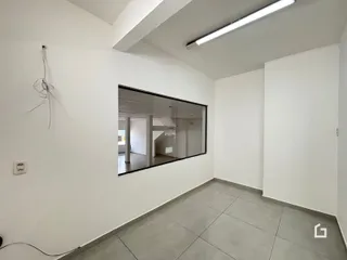 Vista interna de um ambiente com paredes brancas e piso de cerâmica.