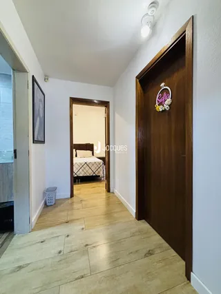 Hall de entrada com piso de madeira e porta de madeira em uma residência.