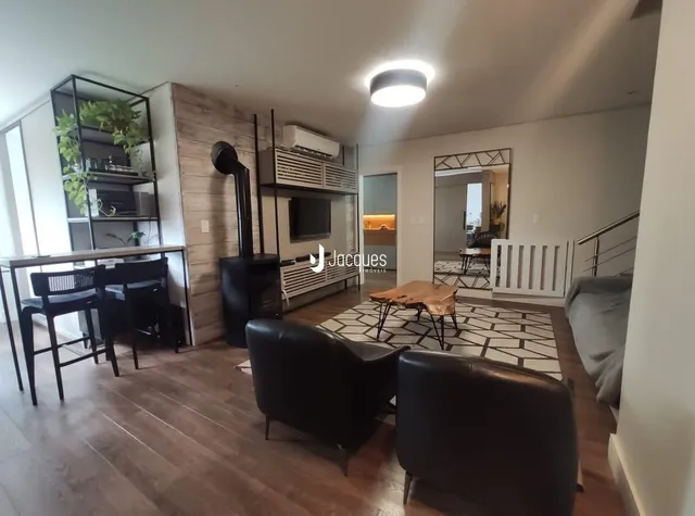 Sala de estar com piso de madeira e móveis escuros.