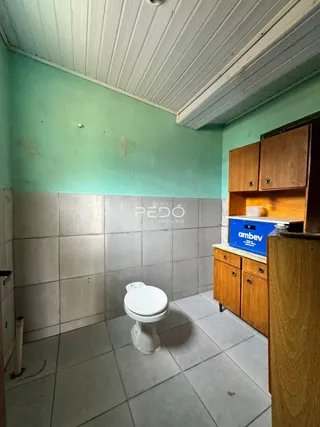 Foto interna de um banheiro com piso de cerâmica e armários de madeira.