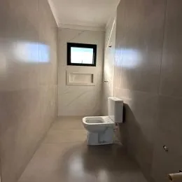 Foto de um corredor com um vaso sanitário branco em um imóvel.