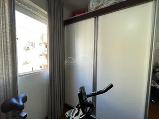 Vista interna de um cômodo com cortinas e uma janela que dá para uma área externa.