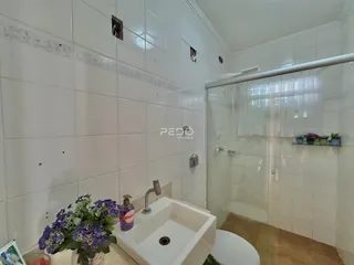 Foto de um banheiro com revestimento cerâmico branco e box de vidro.