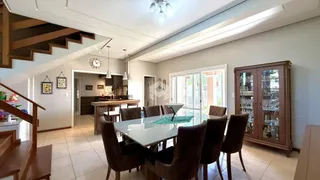 Sala de jantar com mesa de vidro e estantes de madeira.