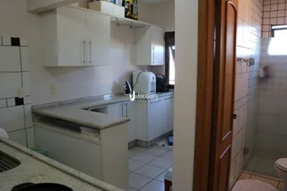 Cozinha com armários brancos e bancadas claras.