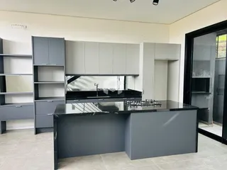 Vista da cozinha moderna com armários cinzas e ilha de granito escuro.