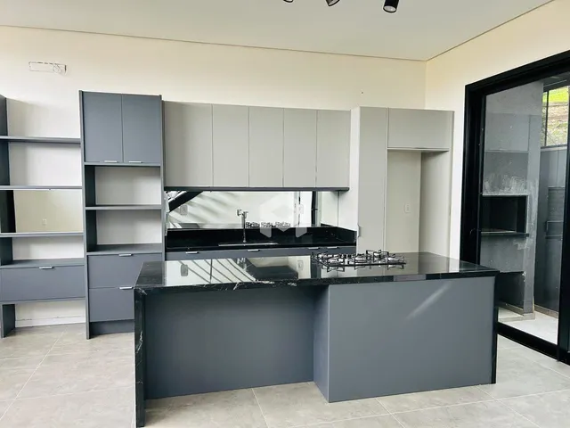 Vista da cozinha moderna com armários cinzas e ilha de granito escuro.