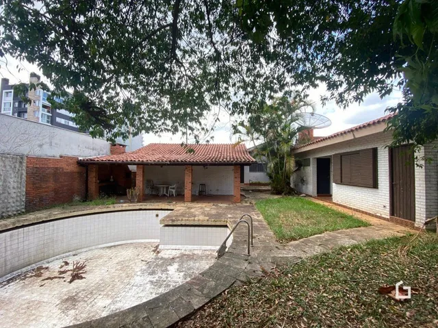 Vista externa de um pátio com muro de tijolos e gramado.