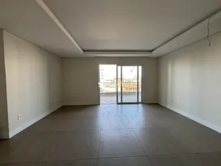 Ambiente interno de uma sala ampla com piso de porcelanato claro.