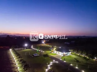 Vista externa de um terreno com gramado e iluminação noturna.