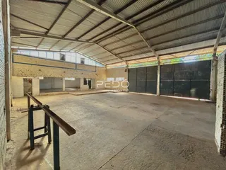 Espaço amplo com estrutura de telhado metálico e piso de concreto.
