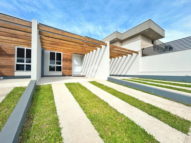 Fachada moderna de uma residência em Lajeado, Brasil, com revestimento de madeira e paisagismo.
