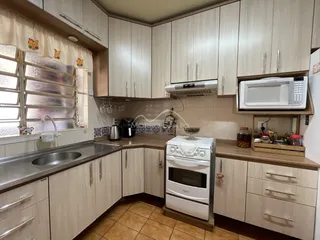 Foto interna de uma cozinha com armários e bancadas em um apartamento.