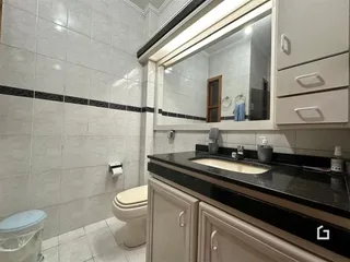 Foto de um banheiro com revestimento cerâmico e bancada escura.