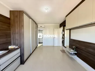 Quarto com armários em madeira e piso claro.