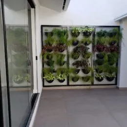 Parede decorada com painel de vegetação verde em um corredor.