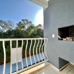 Vista de um terraço com grade branca e paisagem verde ao fundo.