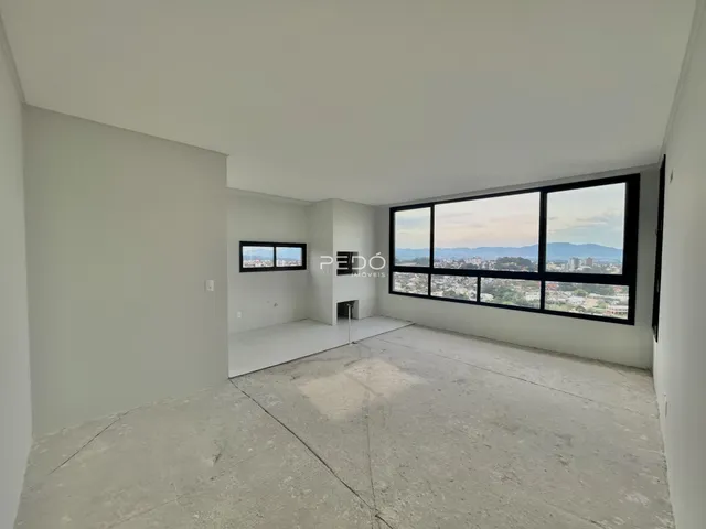 Interior de uma sala ampla com paredes brancas e piso de concreto.