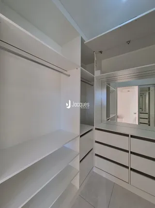 Vista de um corredor com prateleiras brancas e armários embutidos.