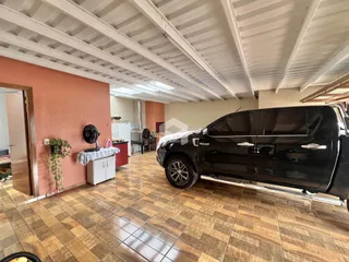 Foto de uma área interna com piso de cerâmica e uma caminhonete estacionada.