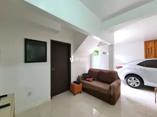 Sala de estar com sofá marrom e parede branca.