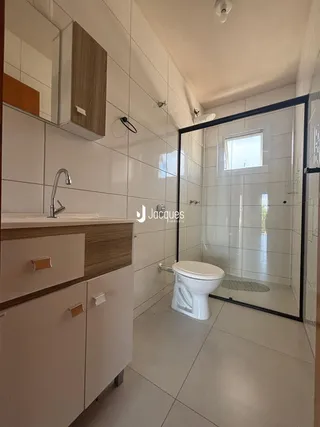 Banheiro com revestimento cerâmico e box de vidro.