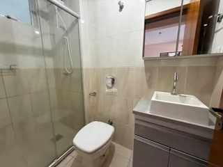 Foto de um banheiro com box de vidro e revestimento de cerâmica clara.