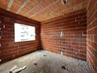 Interior com paredes de tijolo aparente e piso de cascalho.