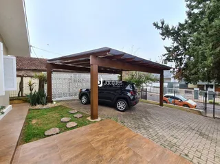 Vista da fachada de uma propriedade com estrutura de madeira e cerca branca.
