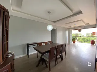 Ambiente interno de uma sala de jantar com mesa de madeira e armário.
