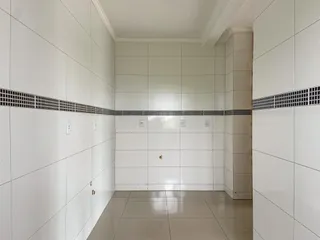 Corredor interno com paredes brancas e piso de cerâmica.