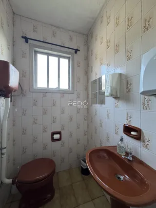 Foto interna de um banheiro com revestimento de azulejos brancos.