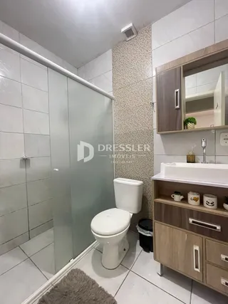 Foto de um banheiro com box de vidro e revestimento cerâmico.