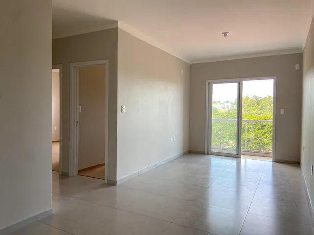 Interior com paredes claras e piso de cerâmica, mostrando uma porta de acesso e uma porta de vidro com vista para o exterior.