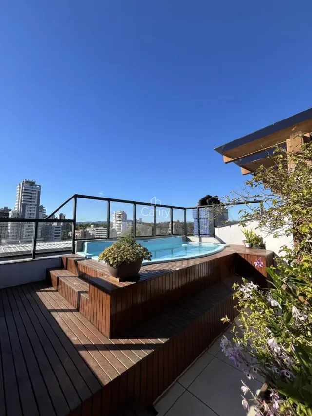 Piscina externa com deck de madeira e vista da paisagem urbana.
