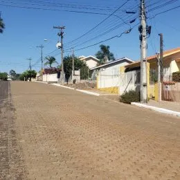 Vista externa de uma rua de terra em uma área residencial.