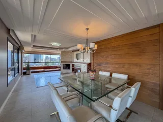 Uma sala de jantar com mesa de vidro e cadeiras brancas em um ambiente com painéis de madeira.