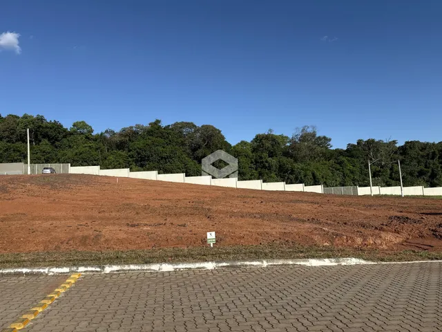 Vista da propriedade com terra vermelha e cerca branca ao fundo.