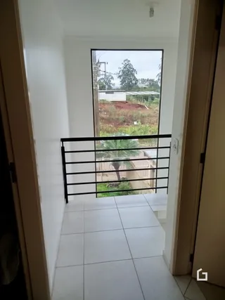 Vista de um ambiente interno com vista para o exterior através de uma grade preta.