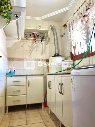 Foto interna de uma cozinha com armários brancos e piso de cerâmica.