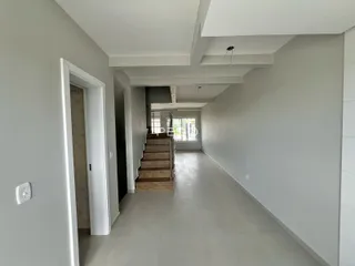 Corredor interno de um apartamento moderno com piso claro e escadaria.
