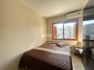 Quarto com cama de casal e janela de madeira em um imóvel no Brasil.
