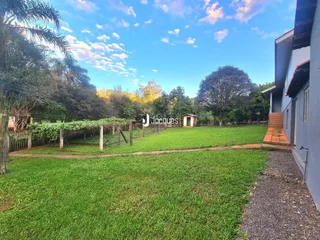 Um gramado verde com cerca de madeira e árvores ao fundo.