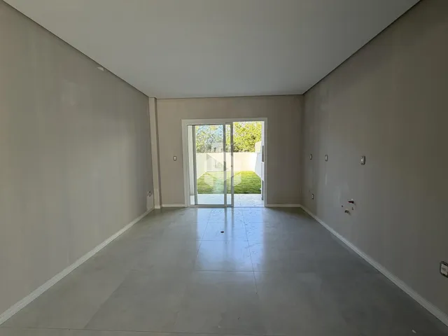 Ambiente interno de uma sala ampla com porta de vidro abrindo para o exterior.
