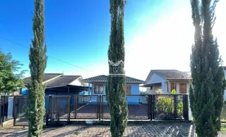Vista externa de uma propriedade em Lajeado, Brasil, com árvores altas e um portão de ferro.