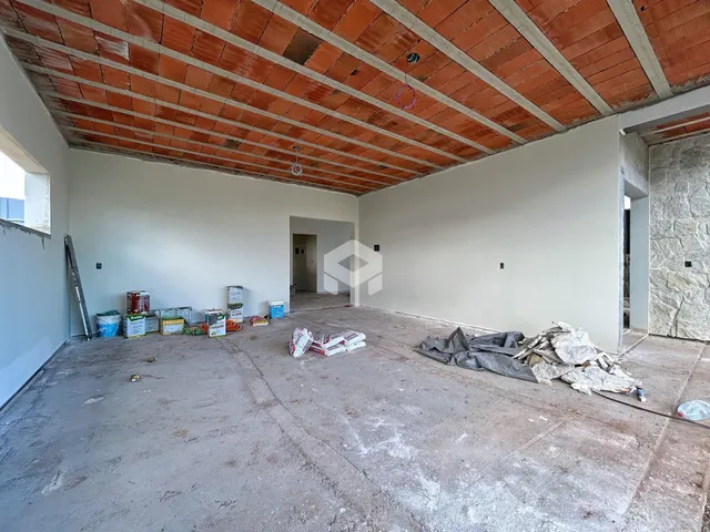 Imagem de um espaço interno de uma residência em construção com piso de concreto.