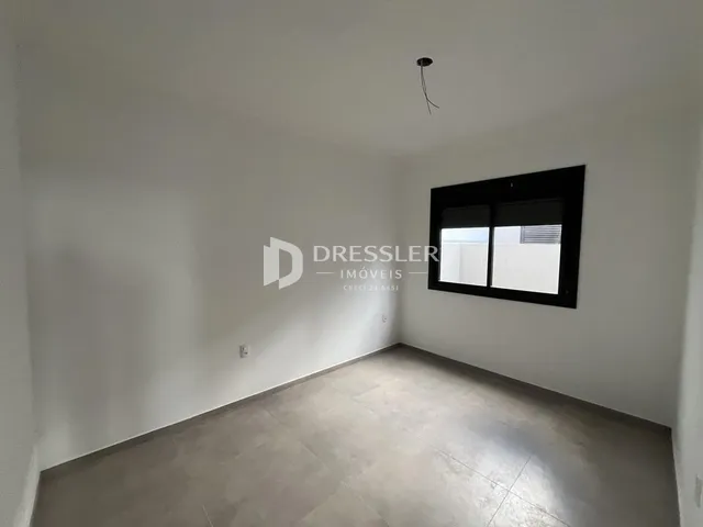 Vista interna de um cômodo com paredes brancas e piso claro.