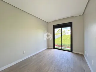 Ambiente interno de uma sala com piso de madeira clara e grande porta de vidro.